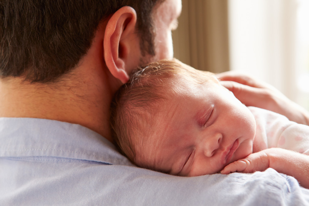 Father At Home With Sleeping Newborn Baby Daughter